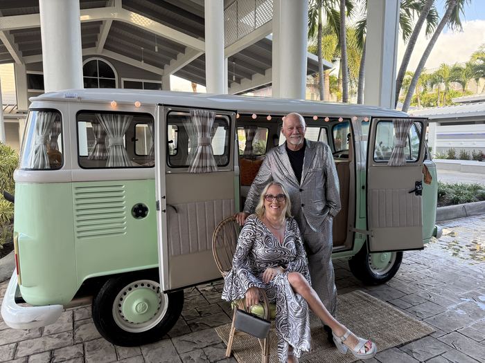 Couple dressed up posing together with Darla the VW bus