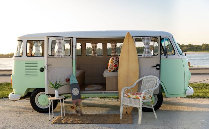 Darla the VW bus decorated with a surfboard and skateboard at sunset