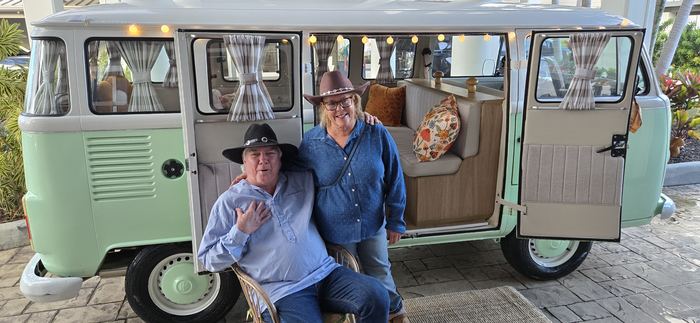 Couple in cowboy hats posing with Darla the VW bus